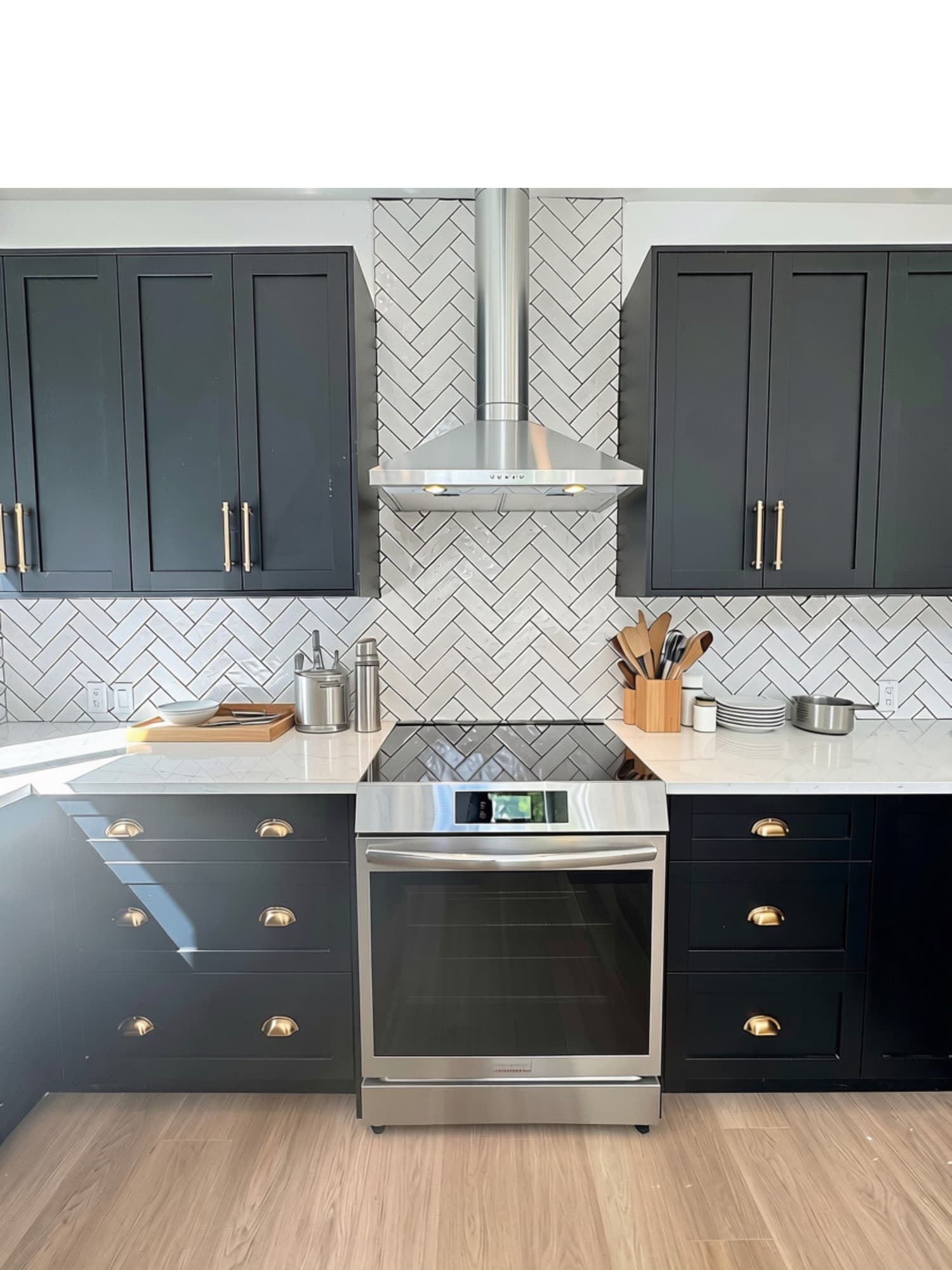 Range wall with herringbone tile, a stainless hood and navy cabinets