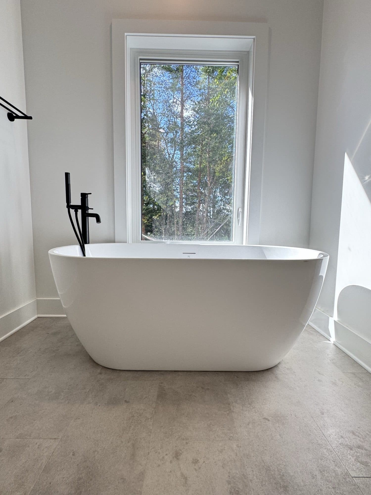 Freestanding soaker tub under a tall window
